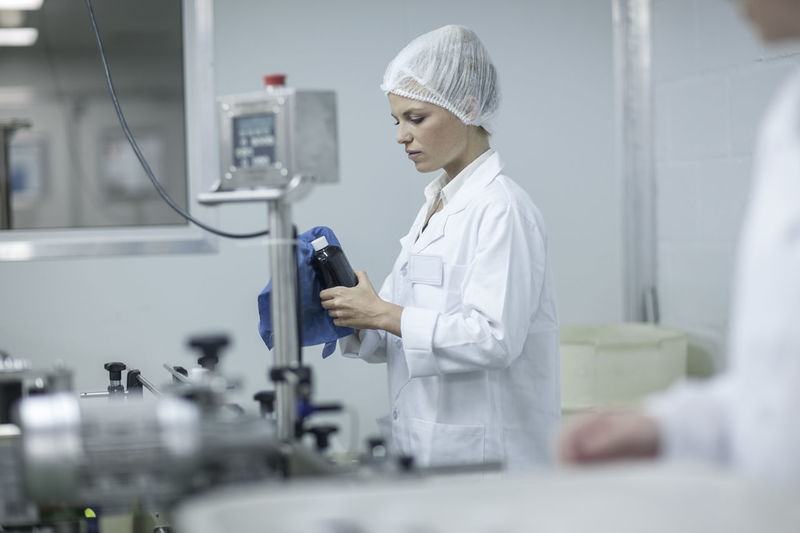 Woman in pharmaceutical plant cleaning flask