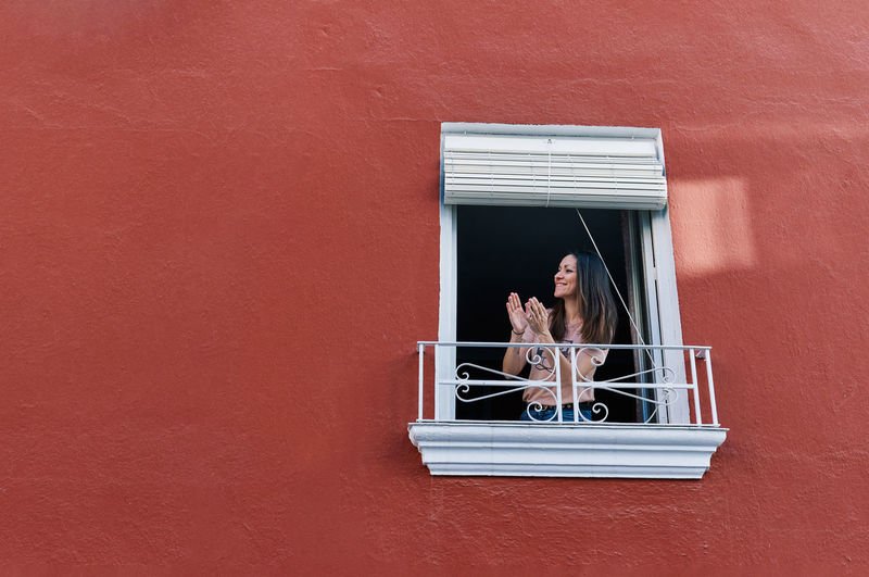 Woman clapping in the window of her house red
