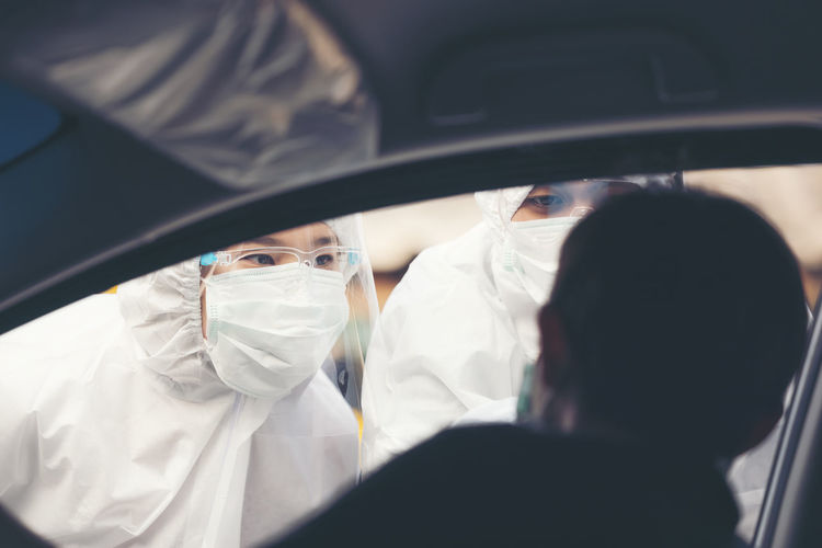 Asian woman drive thru covid-19 testing with ppe medical staff, covid testing temp while checking