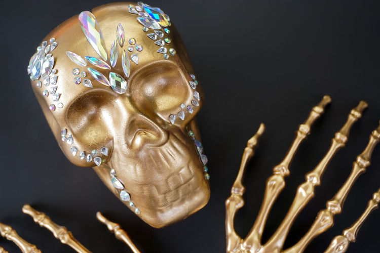 On a black background, a golden skeleton skull decorated with rhinestones