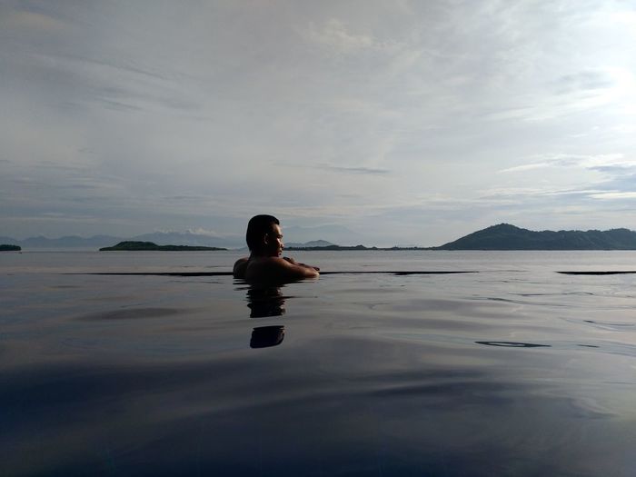 Man swimming in sea against sky