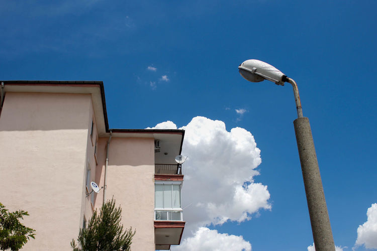 Low angle view of street light by building against sky