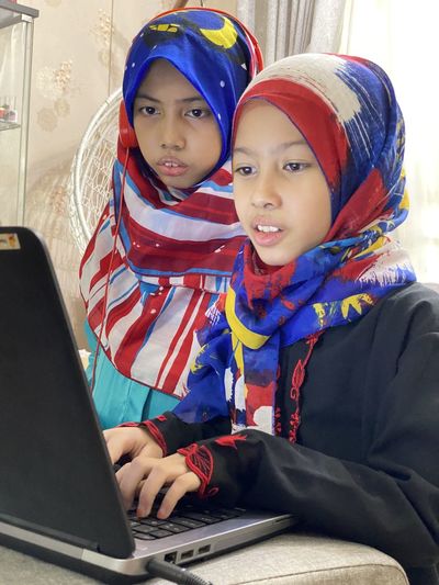Online learning has become a new norm nowadays and a potrait shows two girls are   looking at laptop