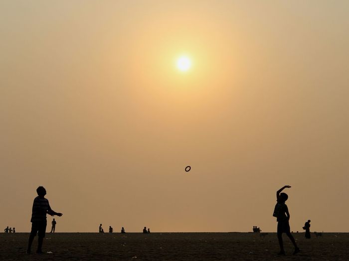 Silhouette people playing against clear sky during sunset