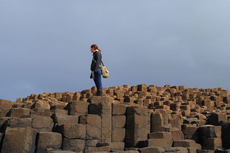 Low angle view of man standing on giants causeway against sky
