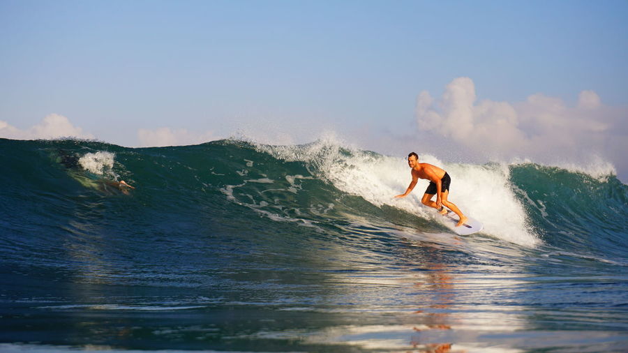Man surfing in sea against sky