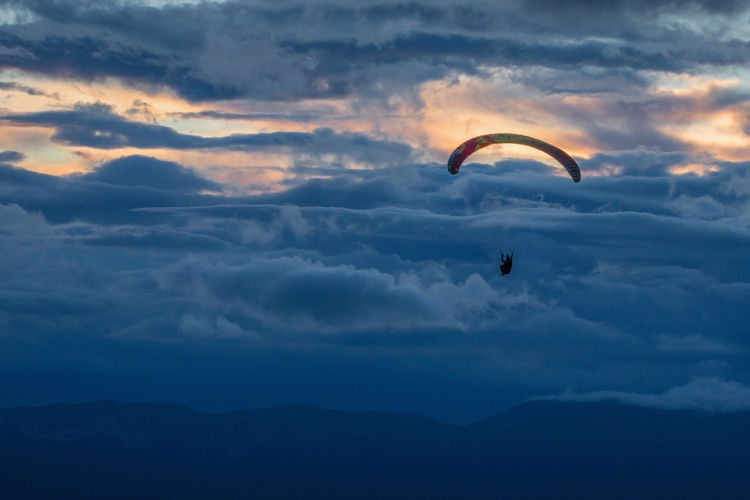 Low angle view of silhouette paragliding against sky