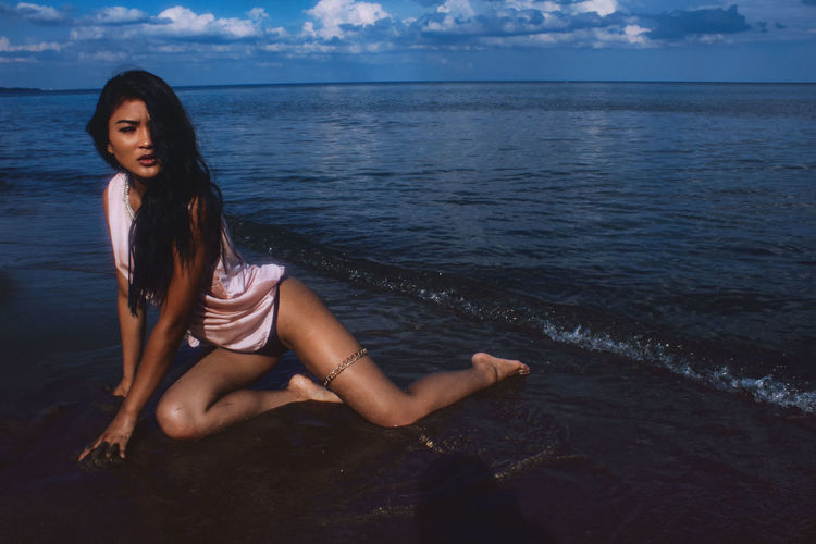Seductive woman sitting on shore at beach