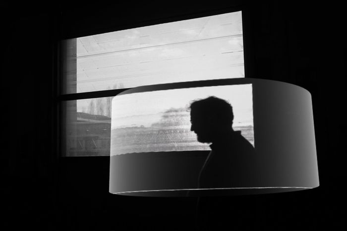 REAR VIEW OF SILHOUETTE WOMAN AGAINST WINDOW IN BLACK BACKGROUND
