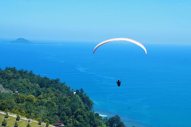 Man paragliding over sea against sky