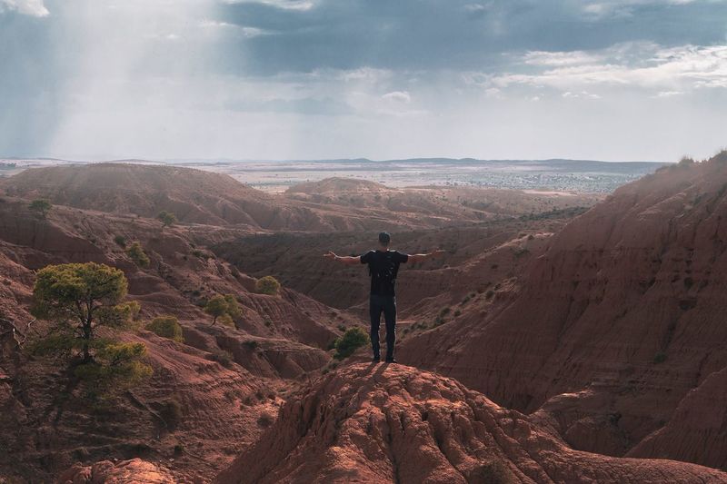 Rear view of man with arms outstretched standing on mountain