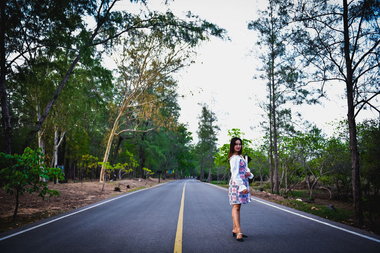 Rear view of man on road amidst trees