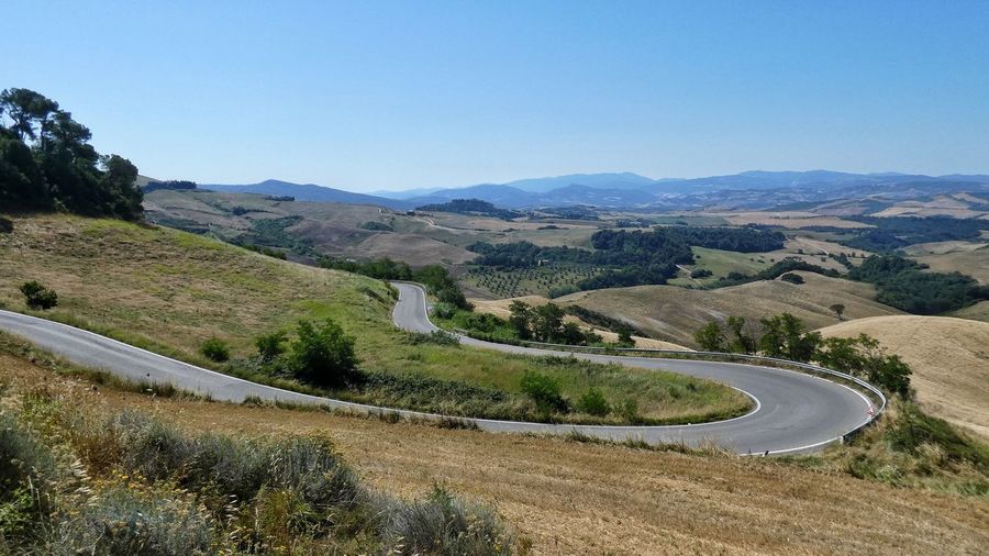 Scenic view of sepentine road to volterra with mountains against clear sky