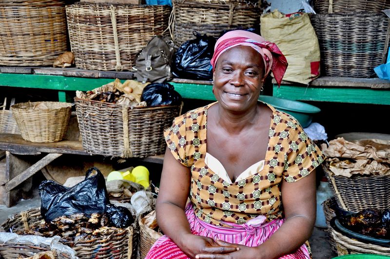 Portrait of female vendor smiling while sitting against wicker baskets at market