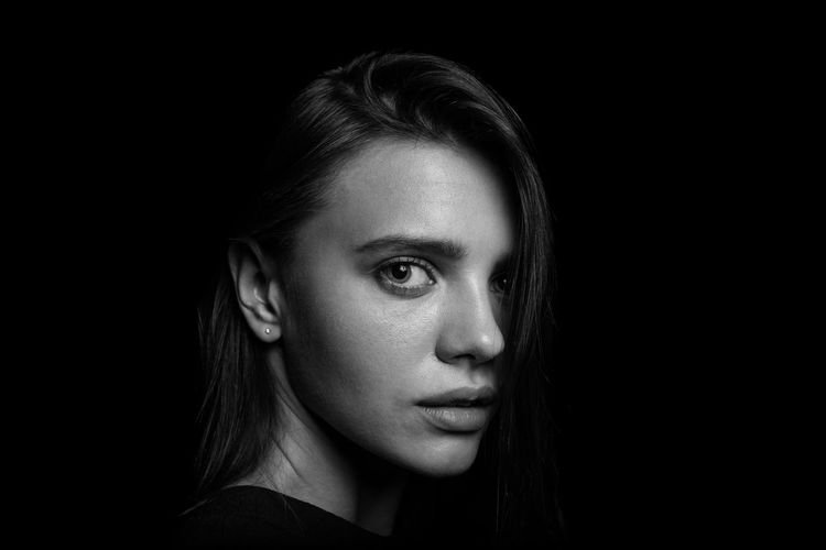 Close-up portrait of young woman over black background