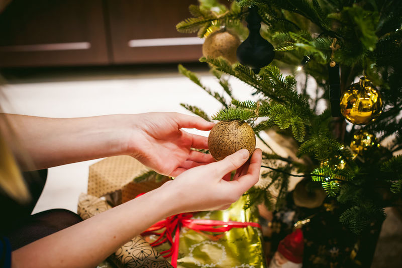 Close-up of woman decorating christmas tree at home