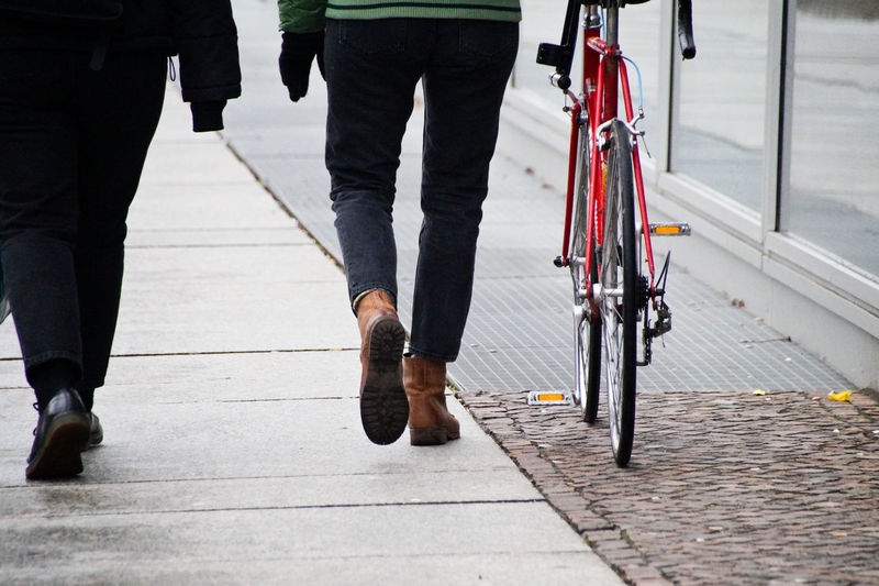 Low section of men walking with bicycle