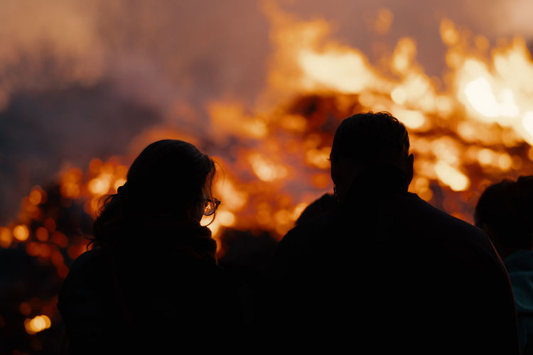 Rear view of silhouette people by fire at night