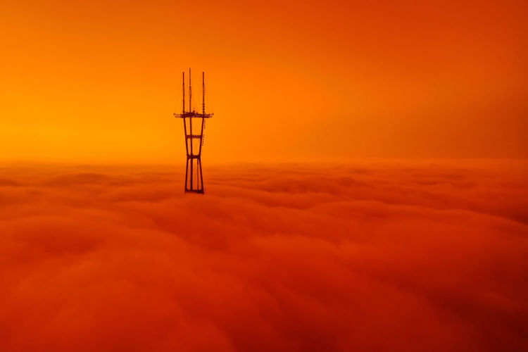 Low angle view of silhouette crane against orange sky