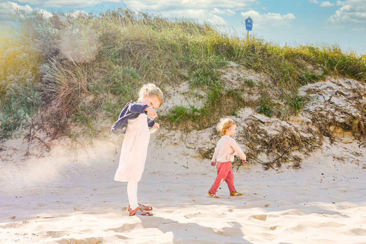 Female sibling children playing and walking near sand dune in langegoog, germany.