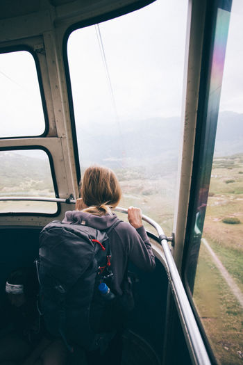 Rear view of woman looking through window in overhead cable car