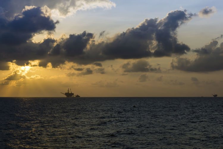 Scenic view of sea against sky during sunset at offshore oil filed with oil platform on background