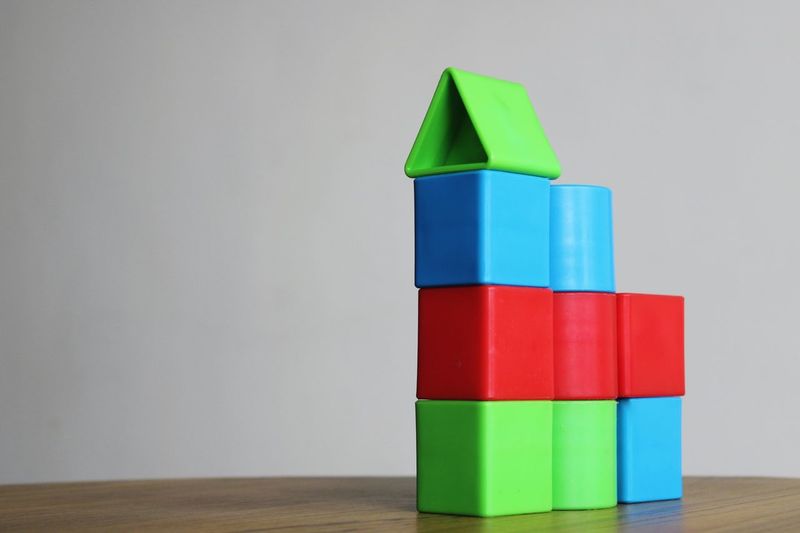 Business growth chart made of stack of multi colored toy blocks on table against white background 
