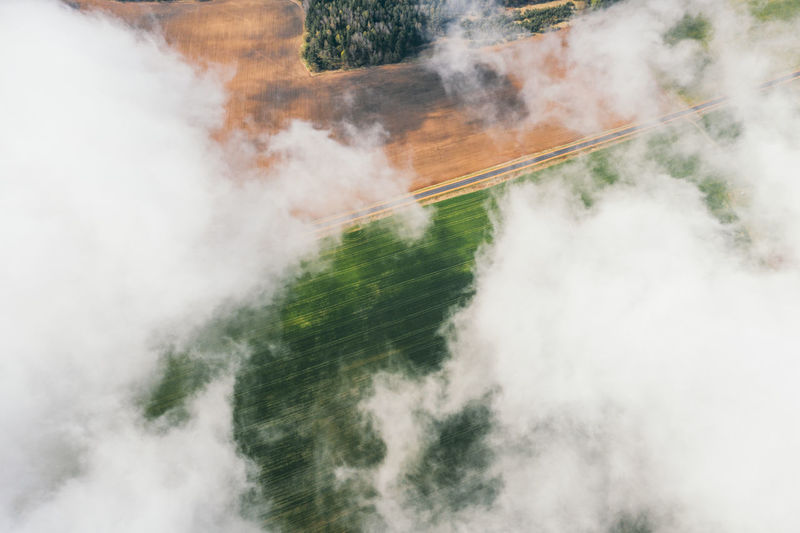 Aerial view of green farmland fields through white clouds