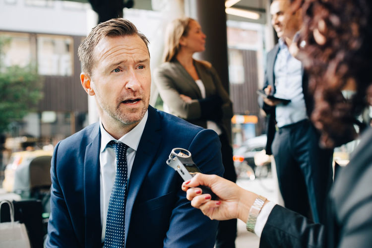 Cropped image of woman interviewing businessman in city