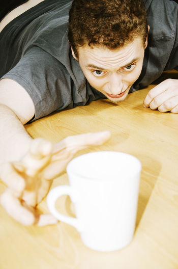 Young man hand reaching towards coffee on breakfast table