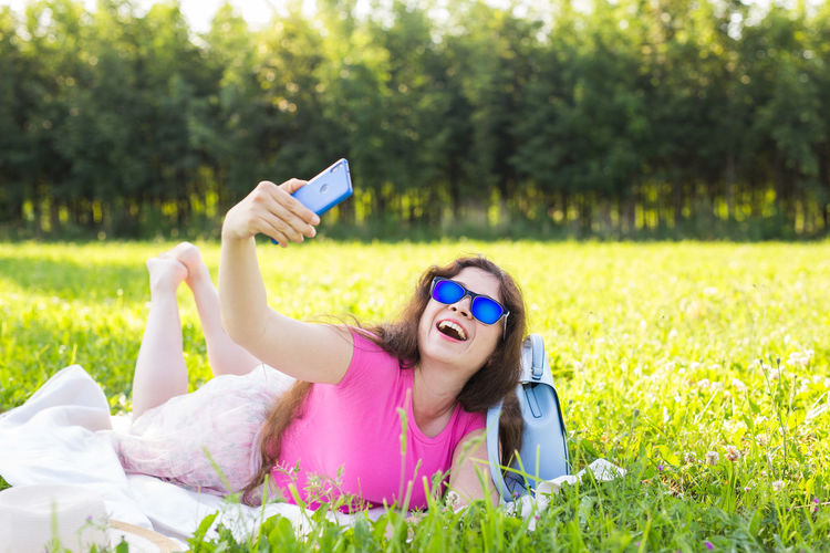 Smiling young woman using mobile phone in grass