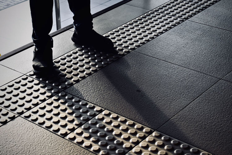 Low section of man walking on tiled floor