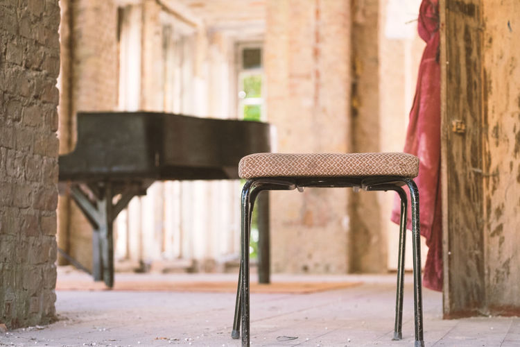 Stool by grand piano in abandoned room