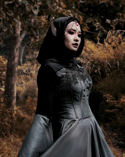 Young woman in halloween costume standing at forest during autumn