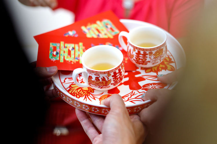 Cropped hands of people holding chinese wedding tea in tray