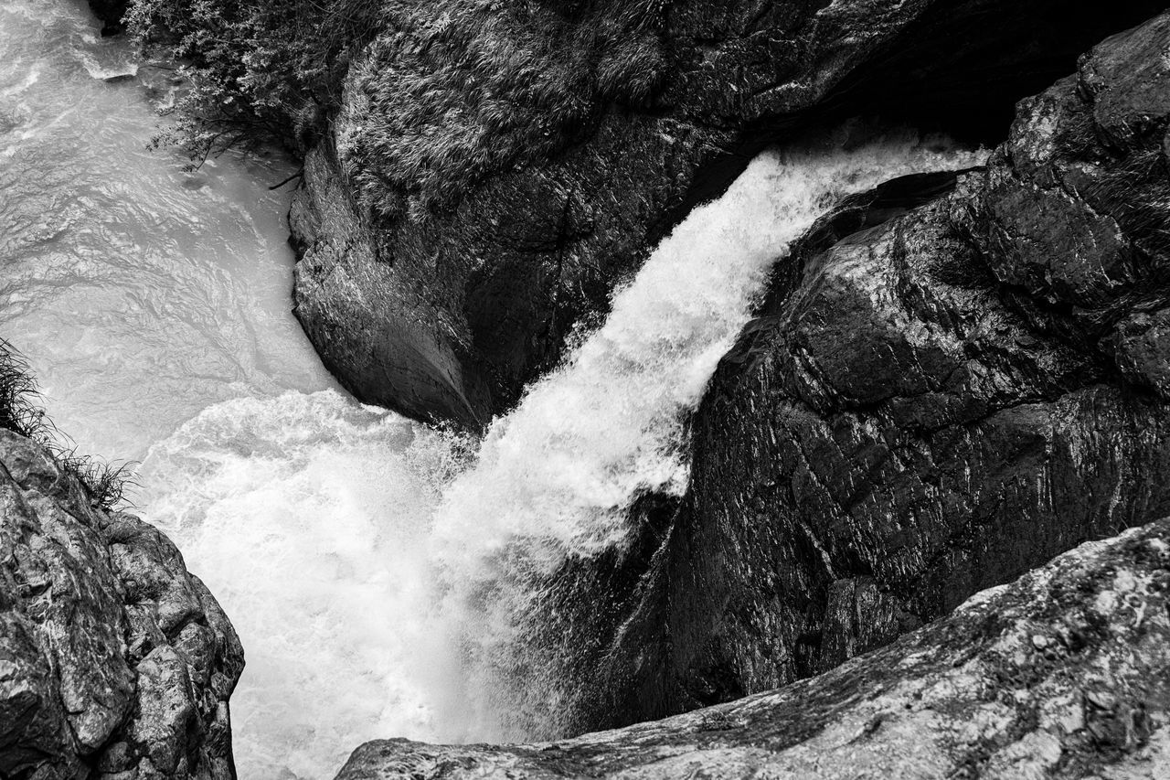 rock, beauty in nature, waterfall, black and white, water, scenics - nature, nature, monochrome photography, rock formation, motion, monochrome, no people, land, geology, day, non-urban scene, power in nature, environment, stream, outdoors, rapid, high angle view, water feature, physical geography, mountain, sea, flowing water, sports, long exposure, flowing, landscape