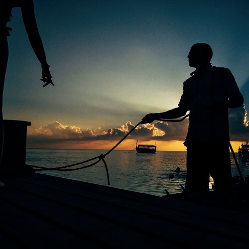 Silhouette of people in sea at sunset