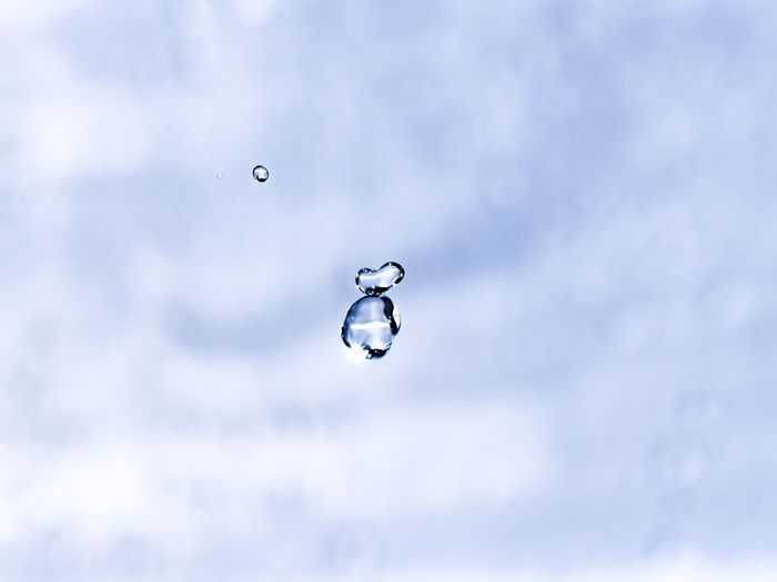 Low angle view of raindrops on bubbles against sky