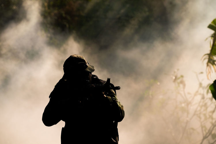 Silhouette soldier against smoke outdoors