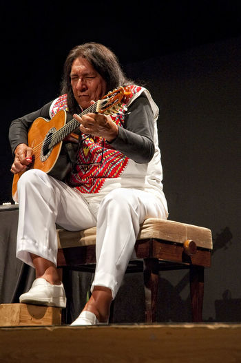 Low angle view of man playing guitar while sitting on seat