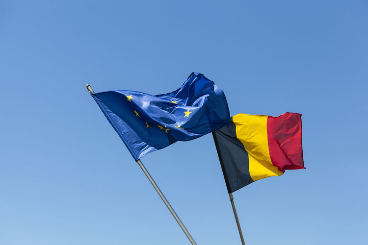 European flag with belgium flag in front of blue sky