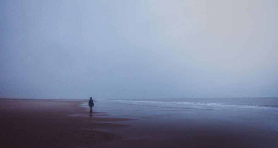 Isolation. person walks on the beach on a misty morning 