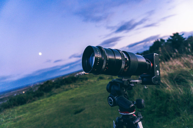 Close-up of camera on field against sky