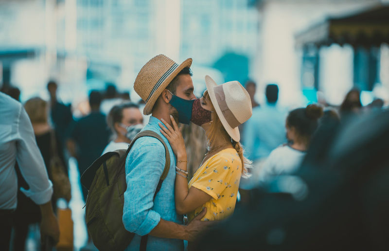 Side view of couple wearing mask kissing outdoors