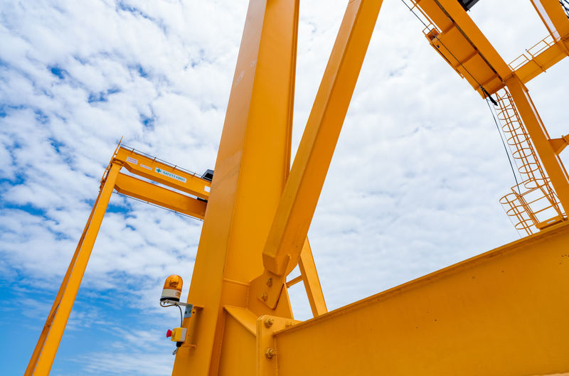 Bottom view of yellow gantry crane against blue sky at port. gantry crane for cargo and construction
