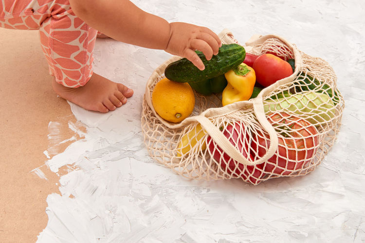 Cropped image of girl picking fruit from bag