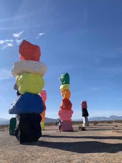 Colorful rocks stacked on land against blue sky