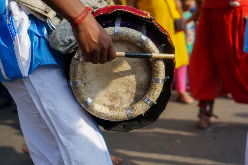 Midsection of man playing drum while standing outdoors