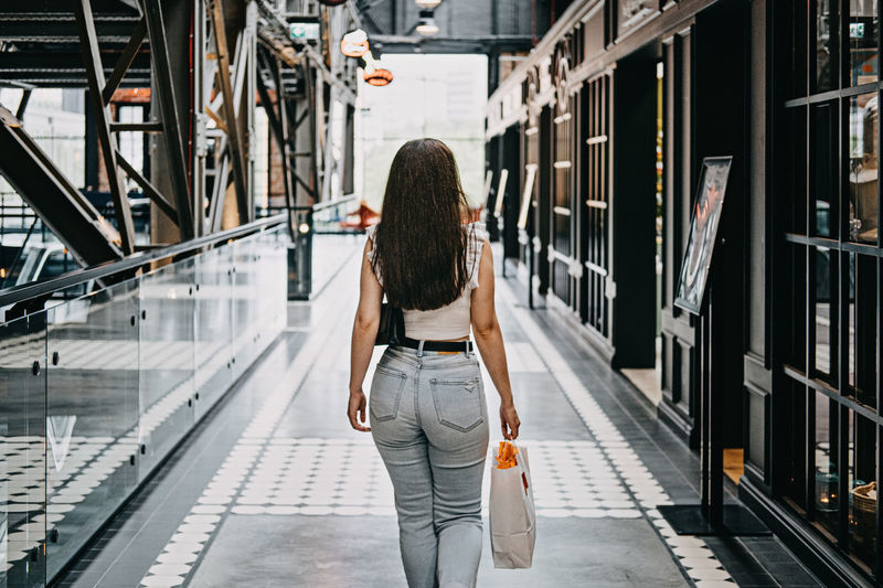 Modern latina young woman walking in large modern mall. young pretty brunette female consumer