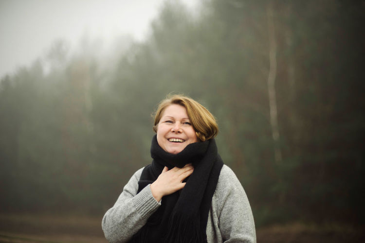 Portrait of smiling woman standing in foggy weather